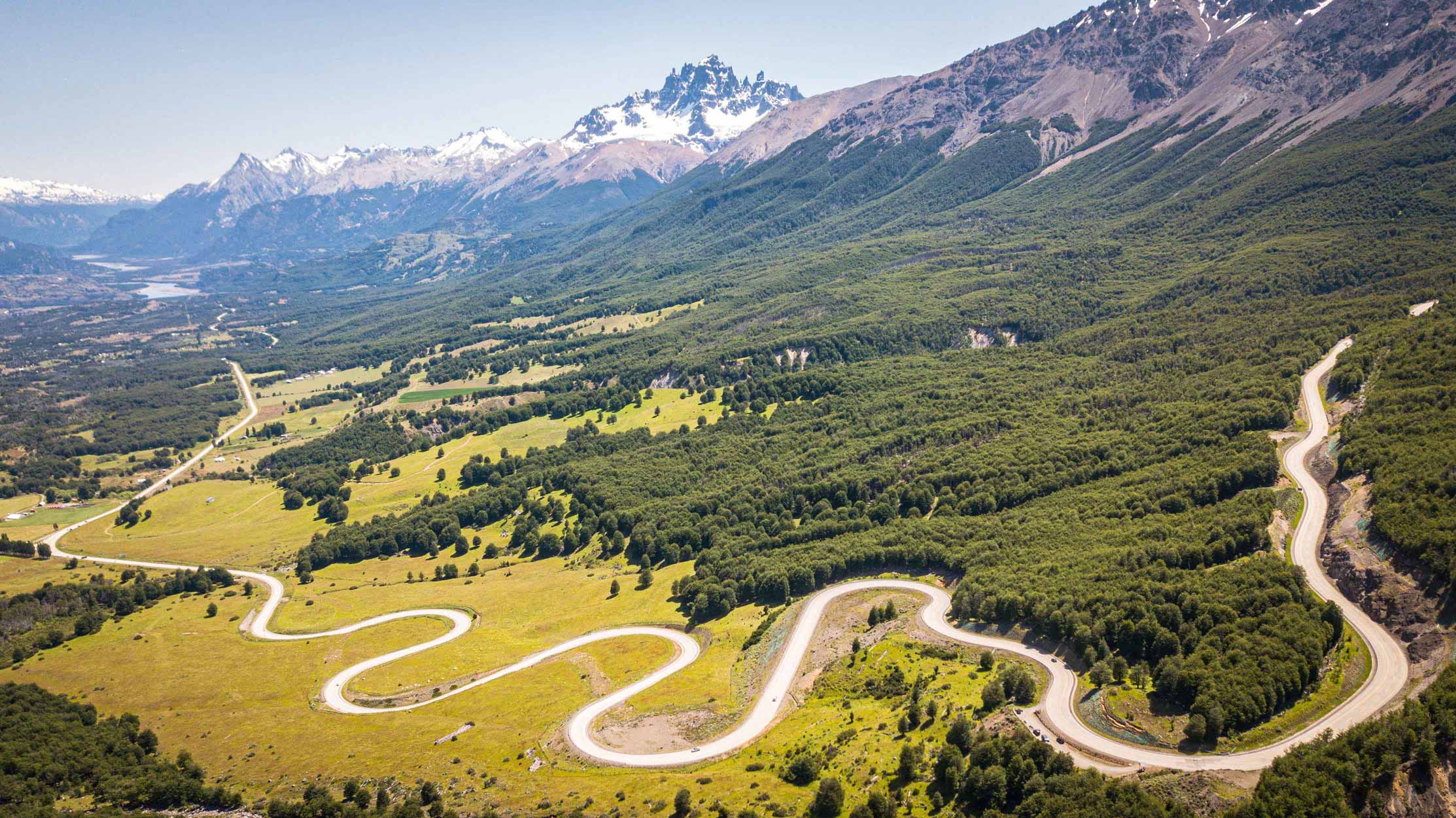 Vista aérea da estrada sinuosa da Carretera Austral, cortando um vale entre montanhas na Patagônia Chilena
